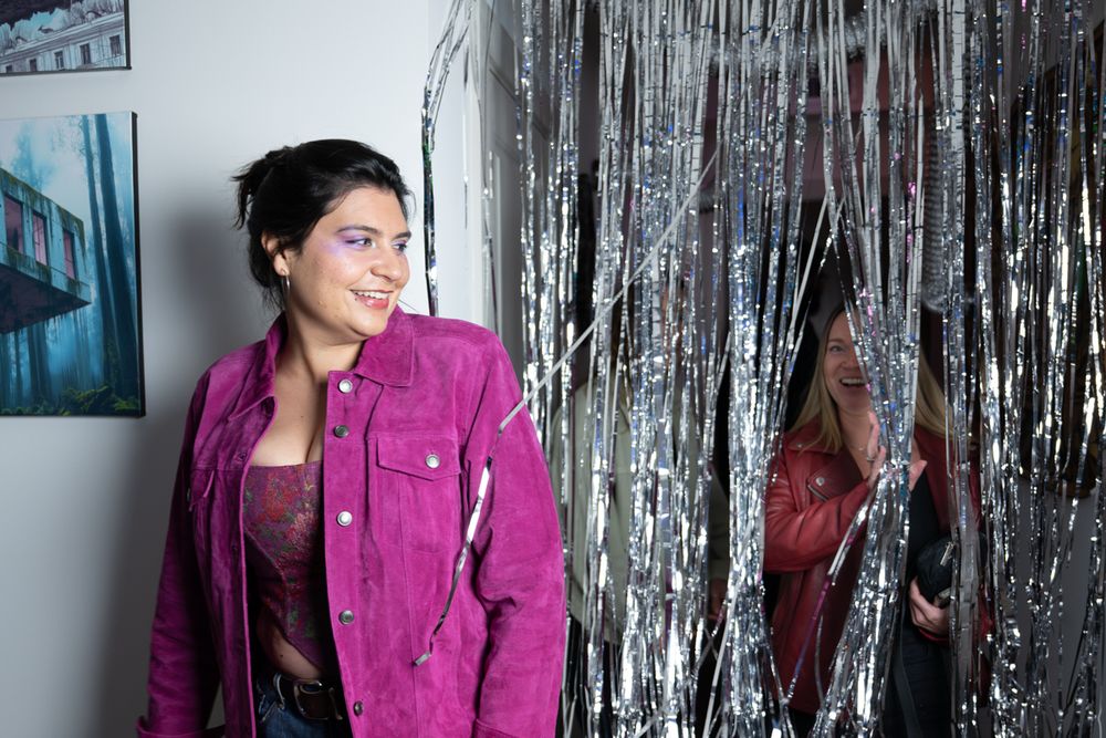 Someone in a magenta jacket poses against a silver tinsel backdrop in multiple similar shots.