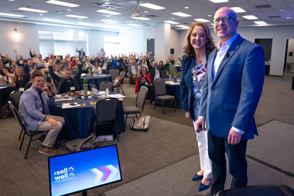 Business professionals gather in a modern conference room for a corporate event with presentation displays.