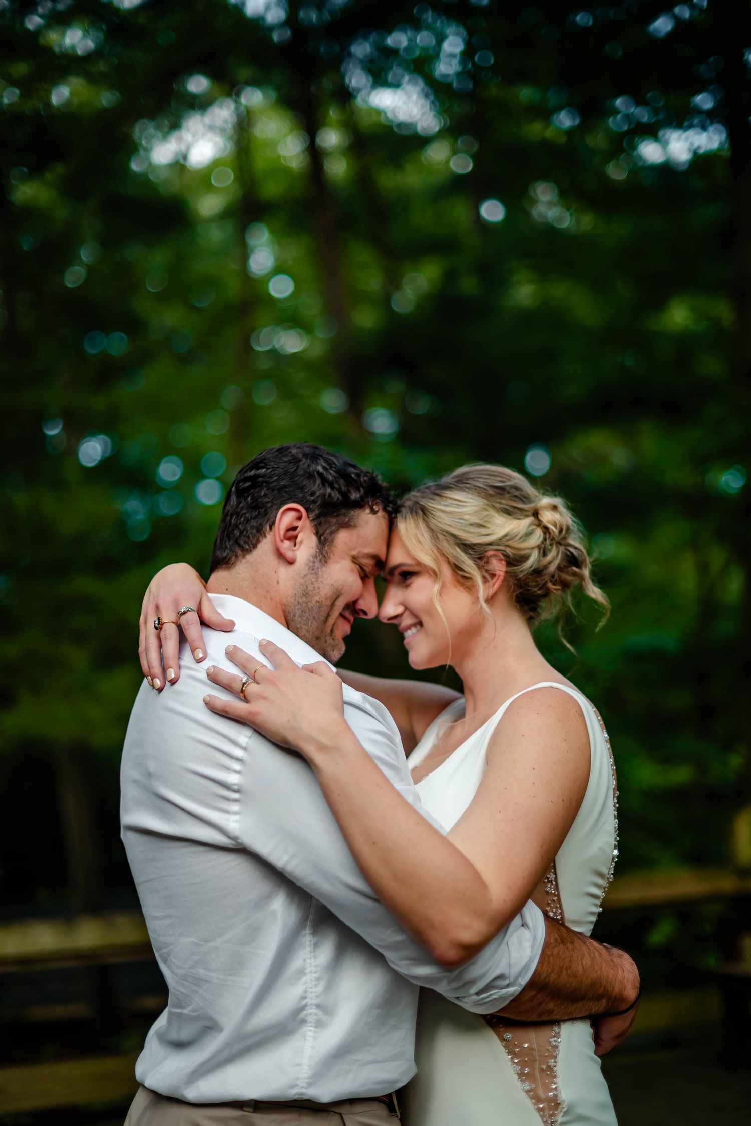 A tender moment between two people embracing in formal attire against a natural backdrop.