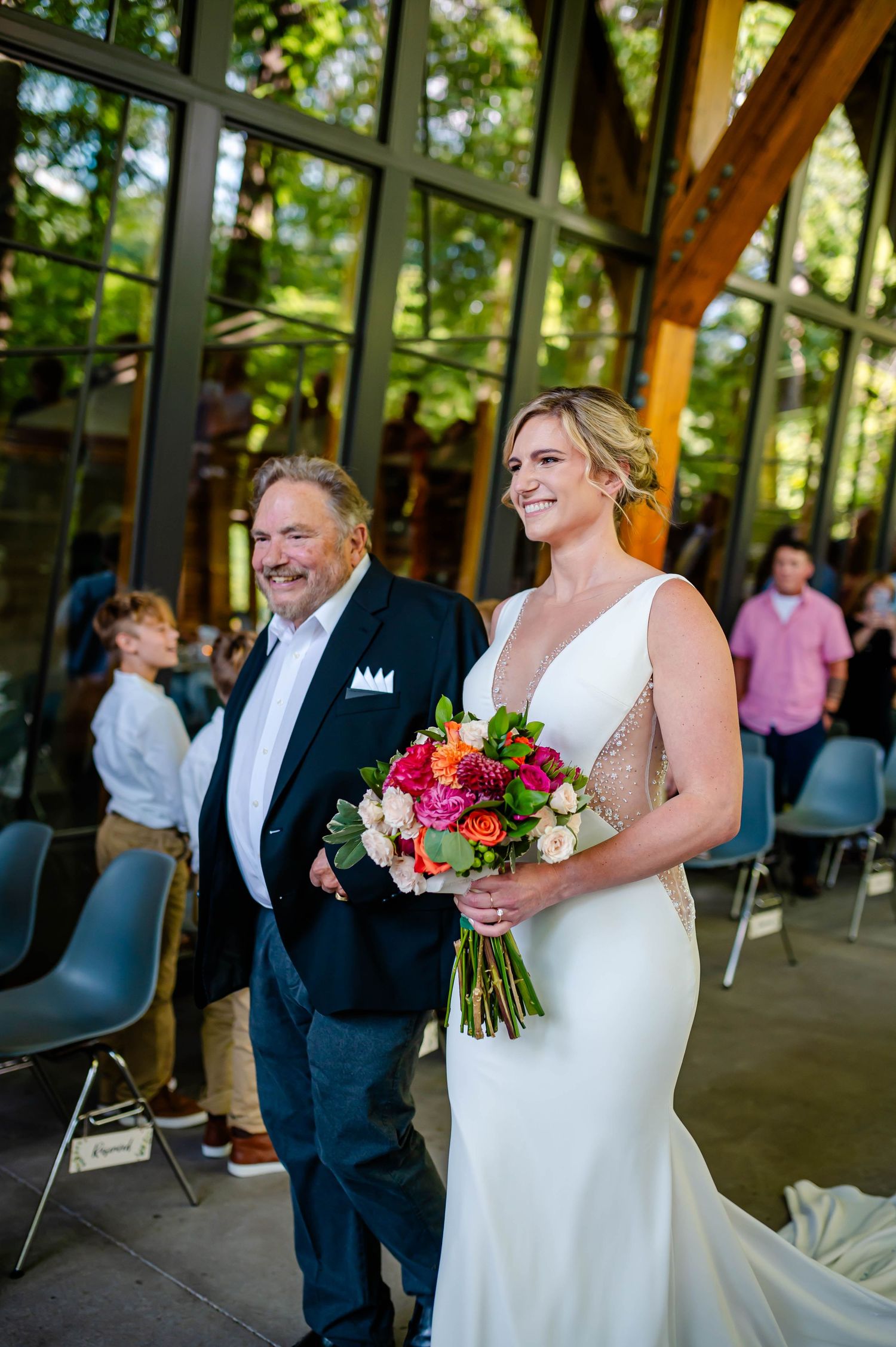Elegant wedding ceremony in a venue with large windows and natural lighting, featuring a beautiful floral bouquet.