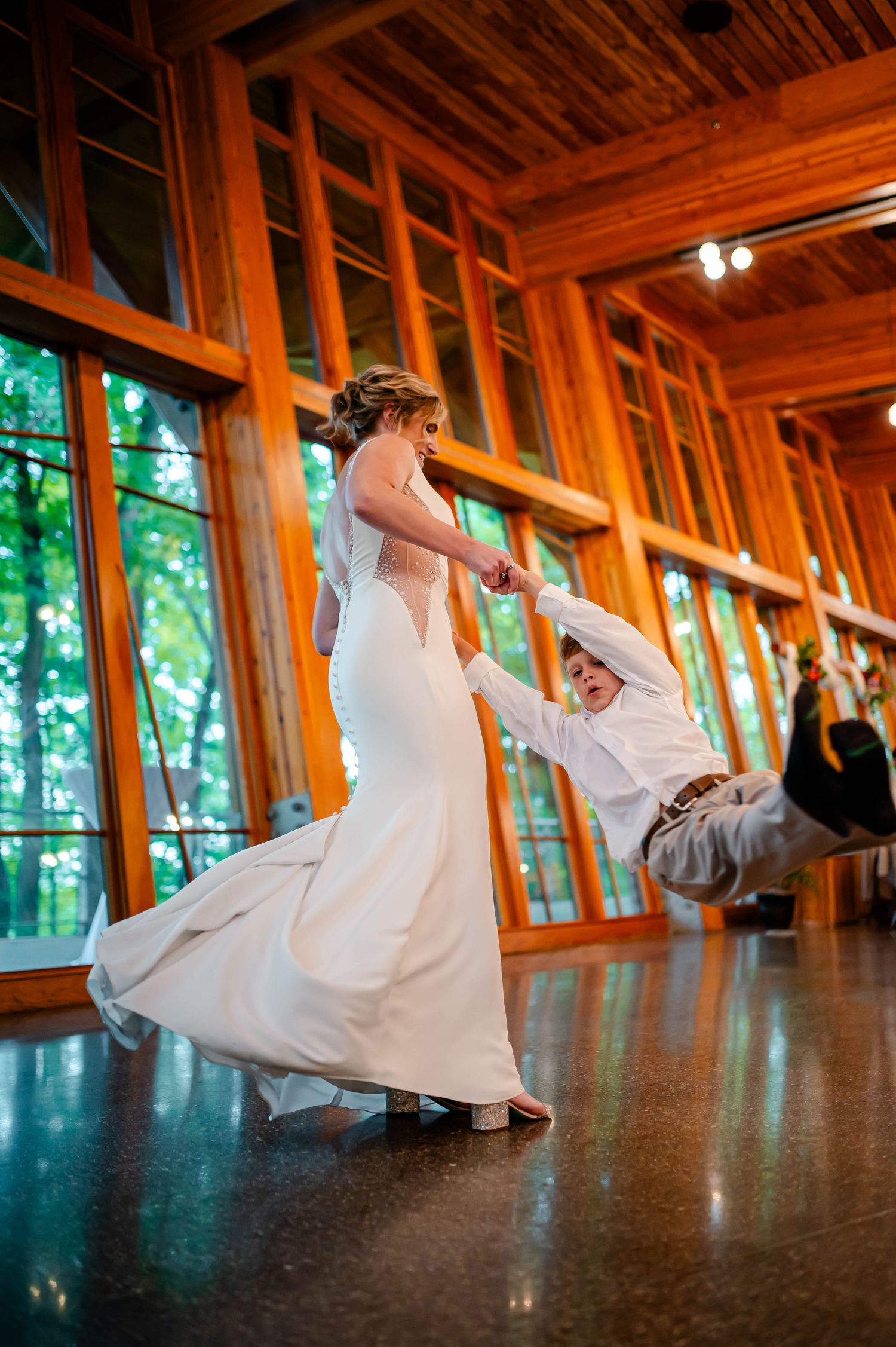 Dramatic tilt dips captured in sequence on dark hardwood floor with sunlit windows in wedding venue.