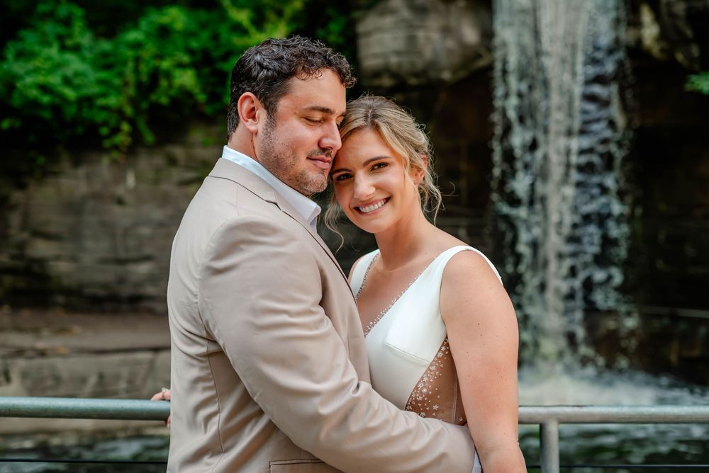A bride and groom share intimate moments against a stone wall backdrop during their outdoor wedding celebration.