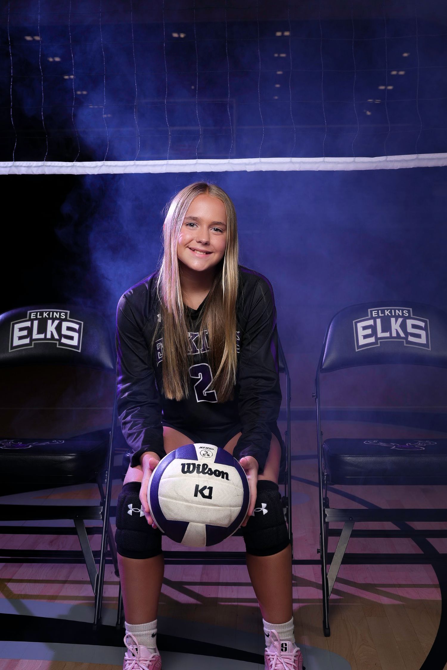 Elkins AR volleyball athlete sitting with ball under lights – Elkins Elks photo.