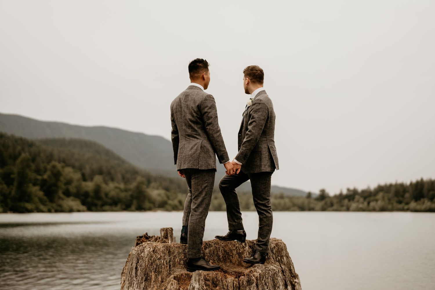 elopment photo of Gay men standing on top of a tree stump holding hands at Rattlesnake Lake after they eloped.