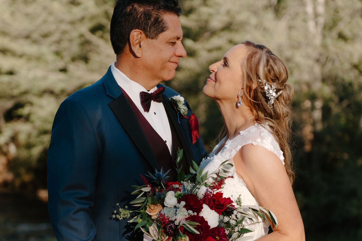Newlywed couple shares intimate kiss in sunset garden setting with soft golden light filtering through trees.