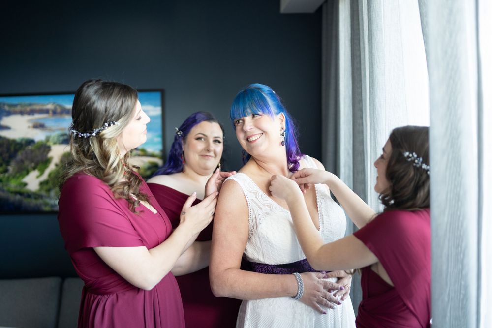 Candid moments of wedding preparation with bridesmaids in burgundy dresses.