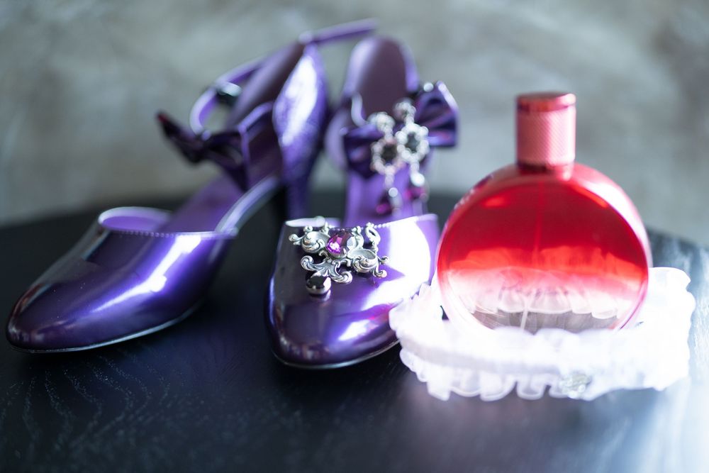 Purple wedding shoes and accessories arranged artistically against a dark background.