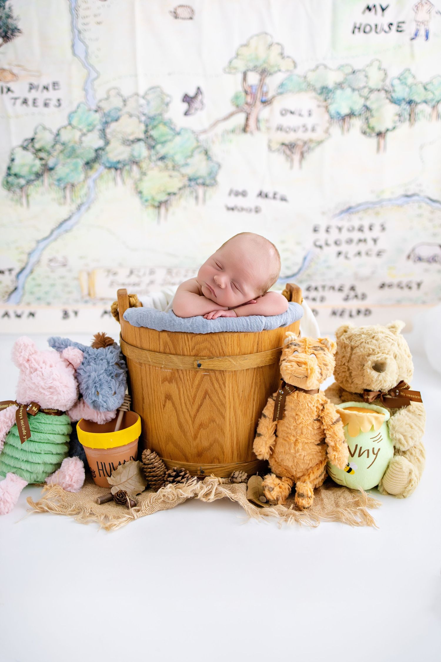 A baby's feet in wooden bucket surrounded by vintage teddy bears and toys on a map background.