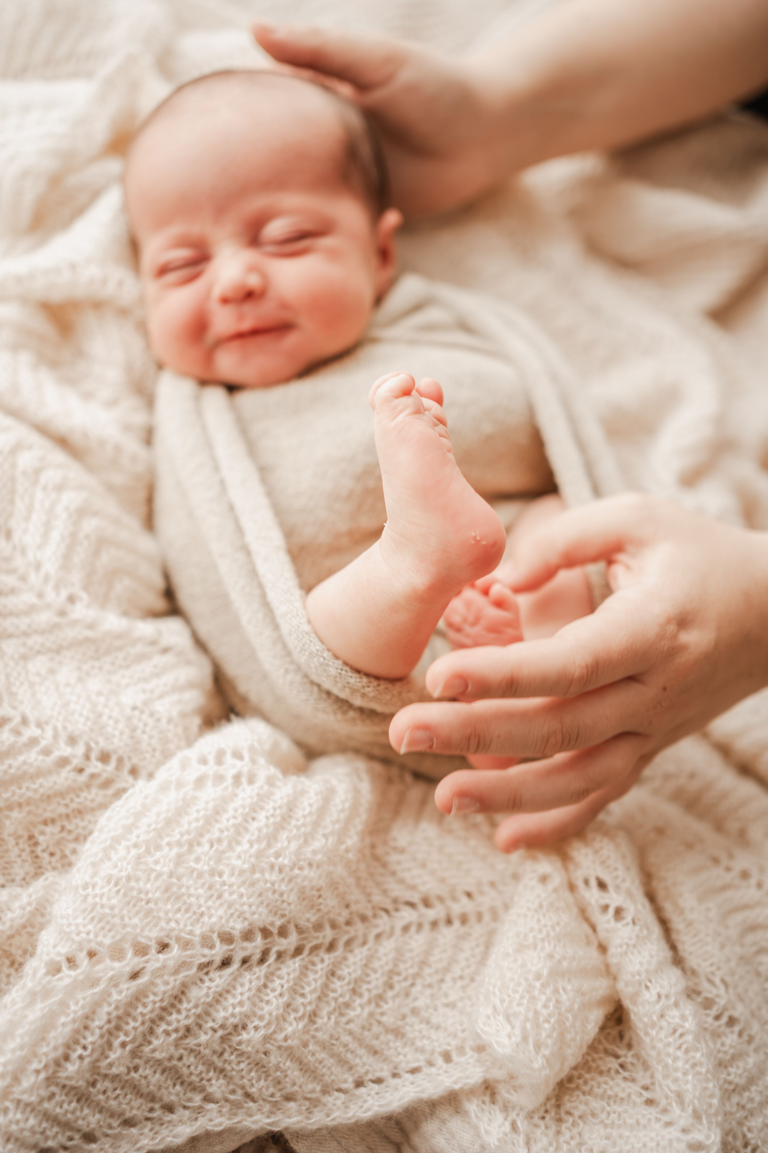 Close-up go newborn baby feet held by mum during cosy in-home photography session in Portland Dorset
