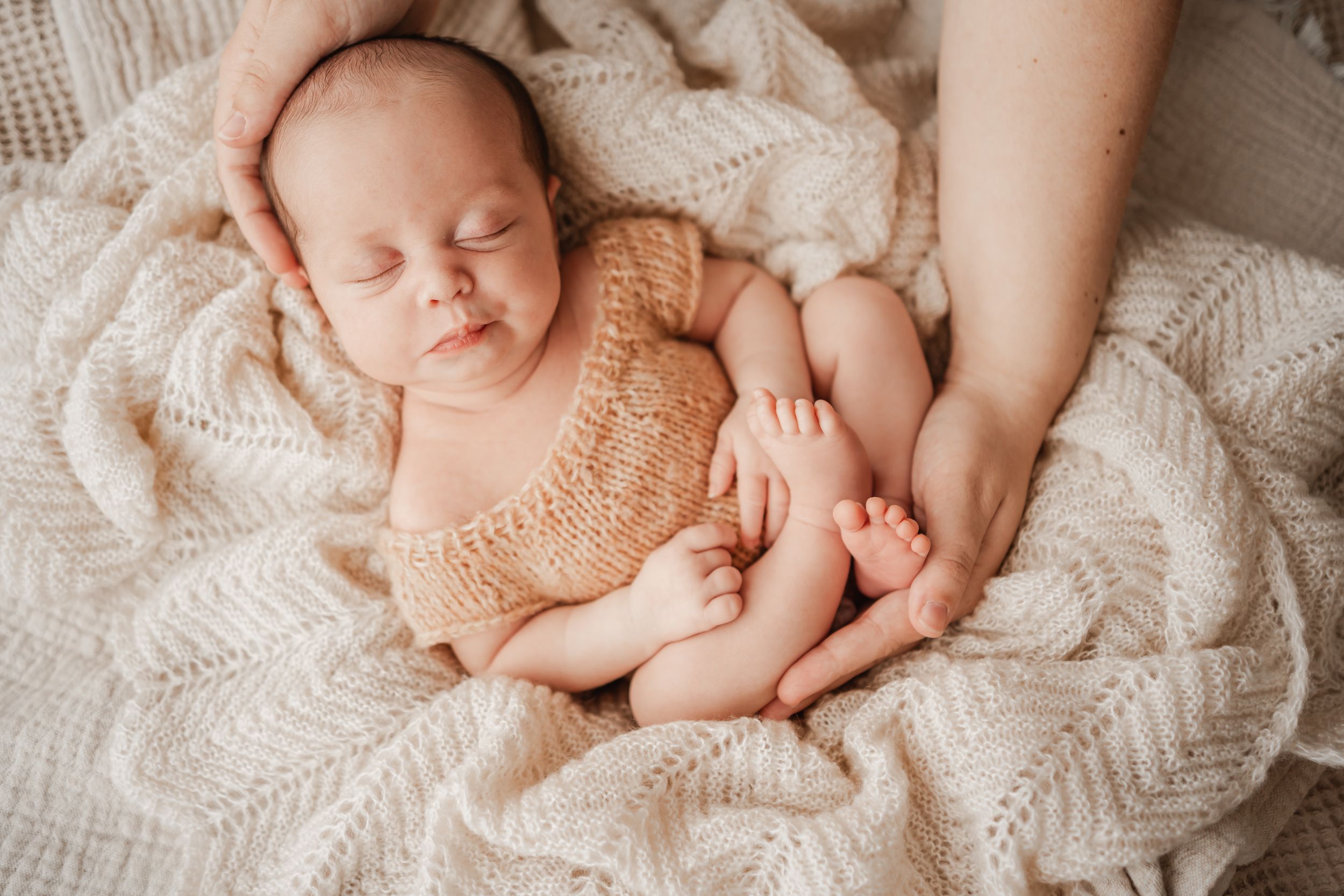 Newborn baby girl knitted romper sleeping on a cream blanket  during in-home Portland, Dorset photography session.