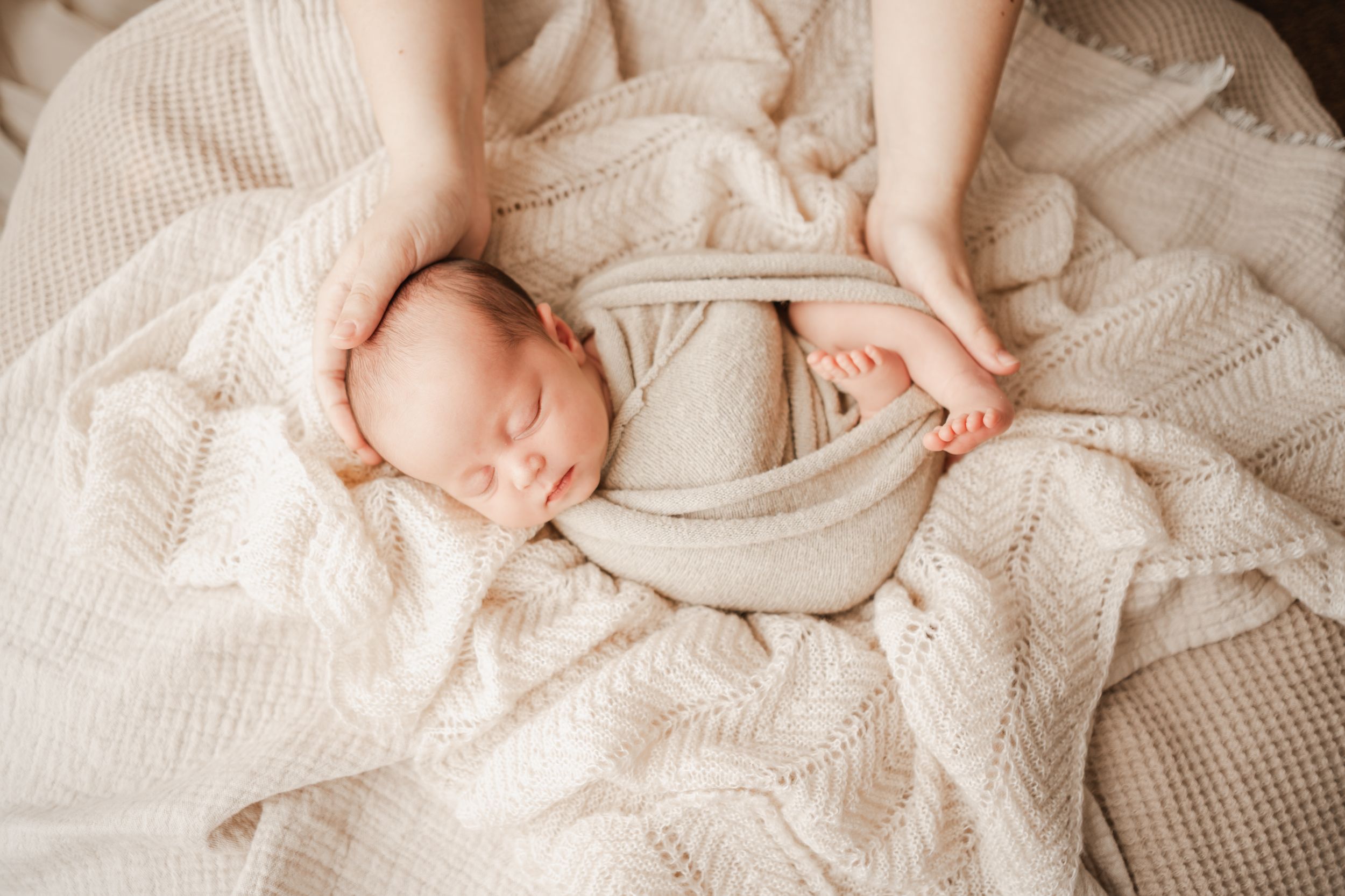Three week old newborn wrapped a a soft blanket, cradled on textured knit during in home Portland, Dorset photography session