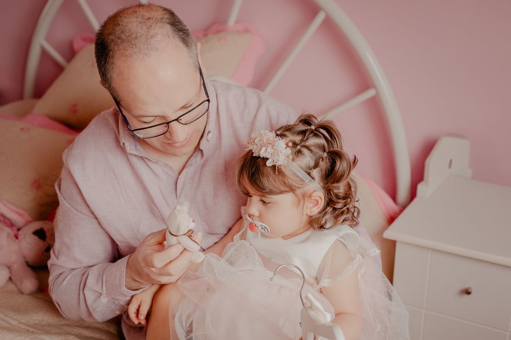 Gentle interaction between family members in a soft pink-hued setting.