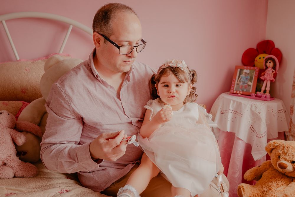 A touching moment during a baptism celebration in a pink-tinted room with religious decor.