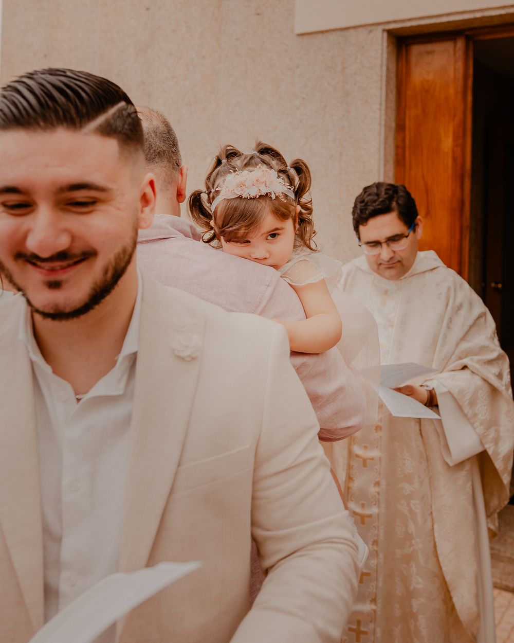 A formal religious ceremony with participants in white attire outside a wooden door.