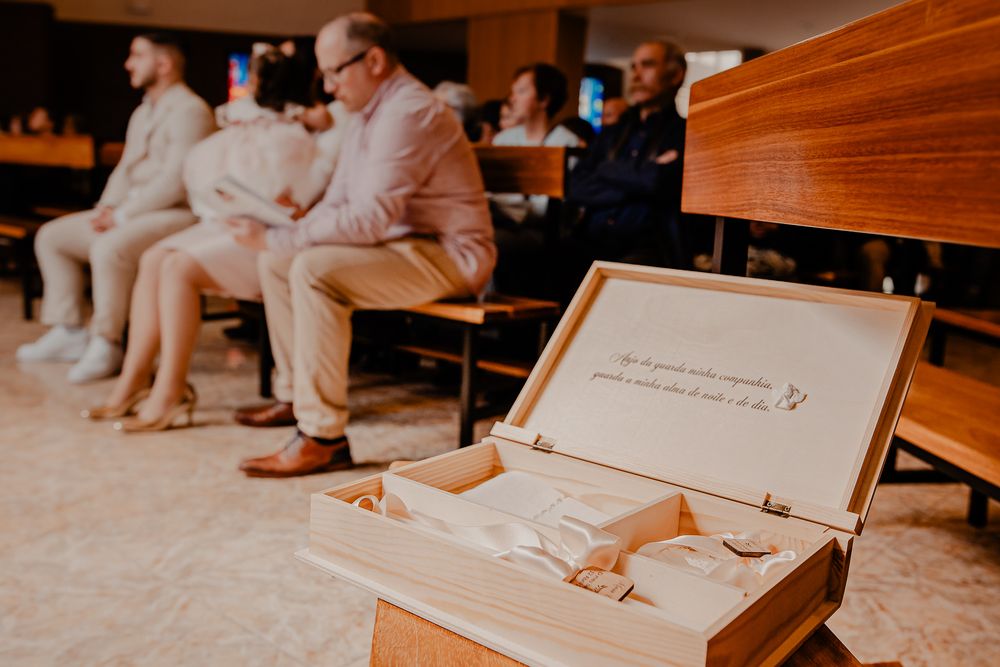 People in formal attire signing documents at a wooden table during a ceremony.