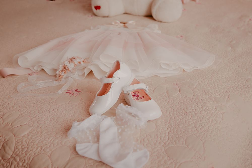 White decorative elements and lace details arranged on a soft pink surface.