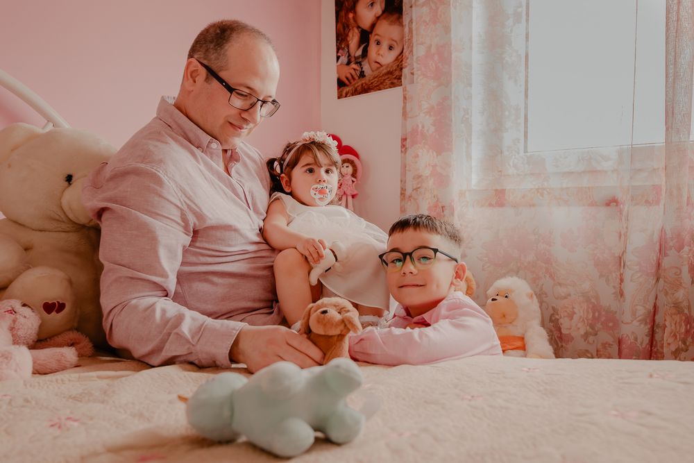 Intimate family gathering captured in warm pink tones against a bedroom backdrop.