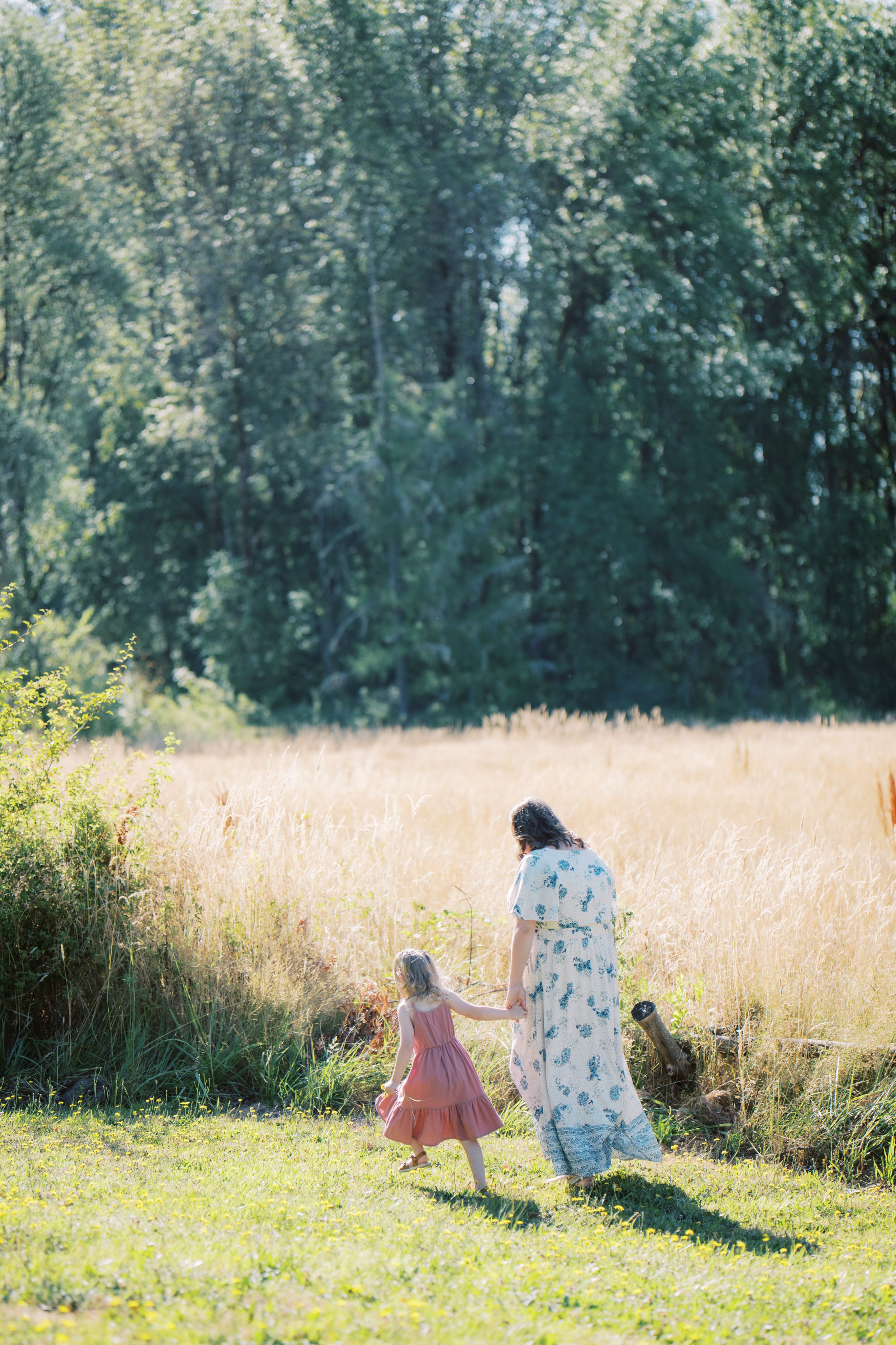 Children playing in a sunny meadow surrounded by tall grasses and trees on a bright summer day.