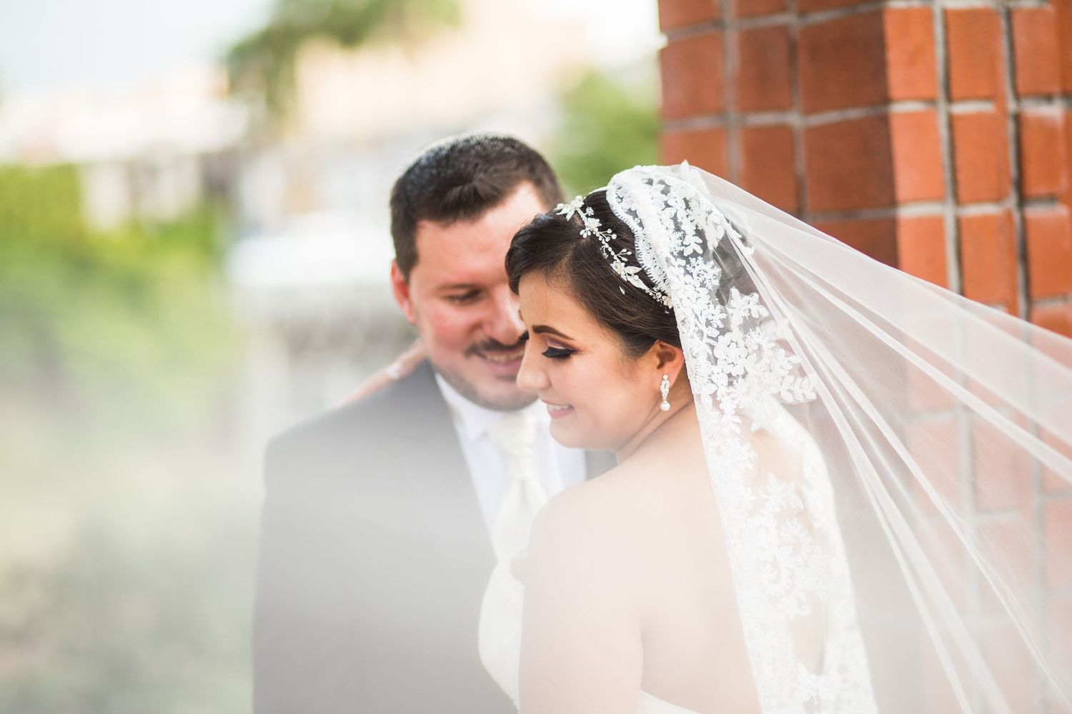 An intimate wedding moment photographed through a soft-focus lens with a delicate veil detail.