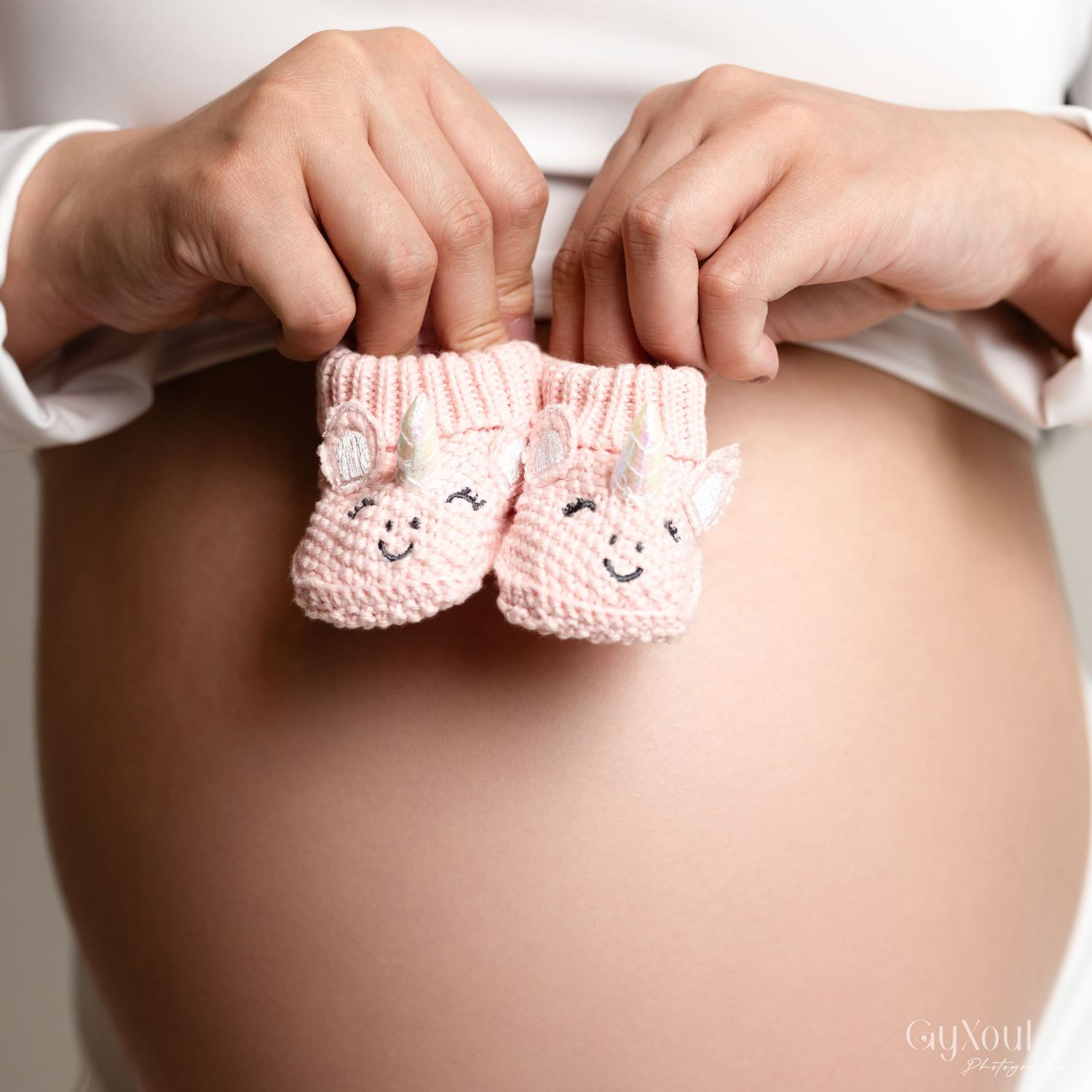 Pink baby booties held against a pregnant belly in multiple poses creating a sweet pregnancy announcement photo collage.