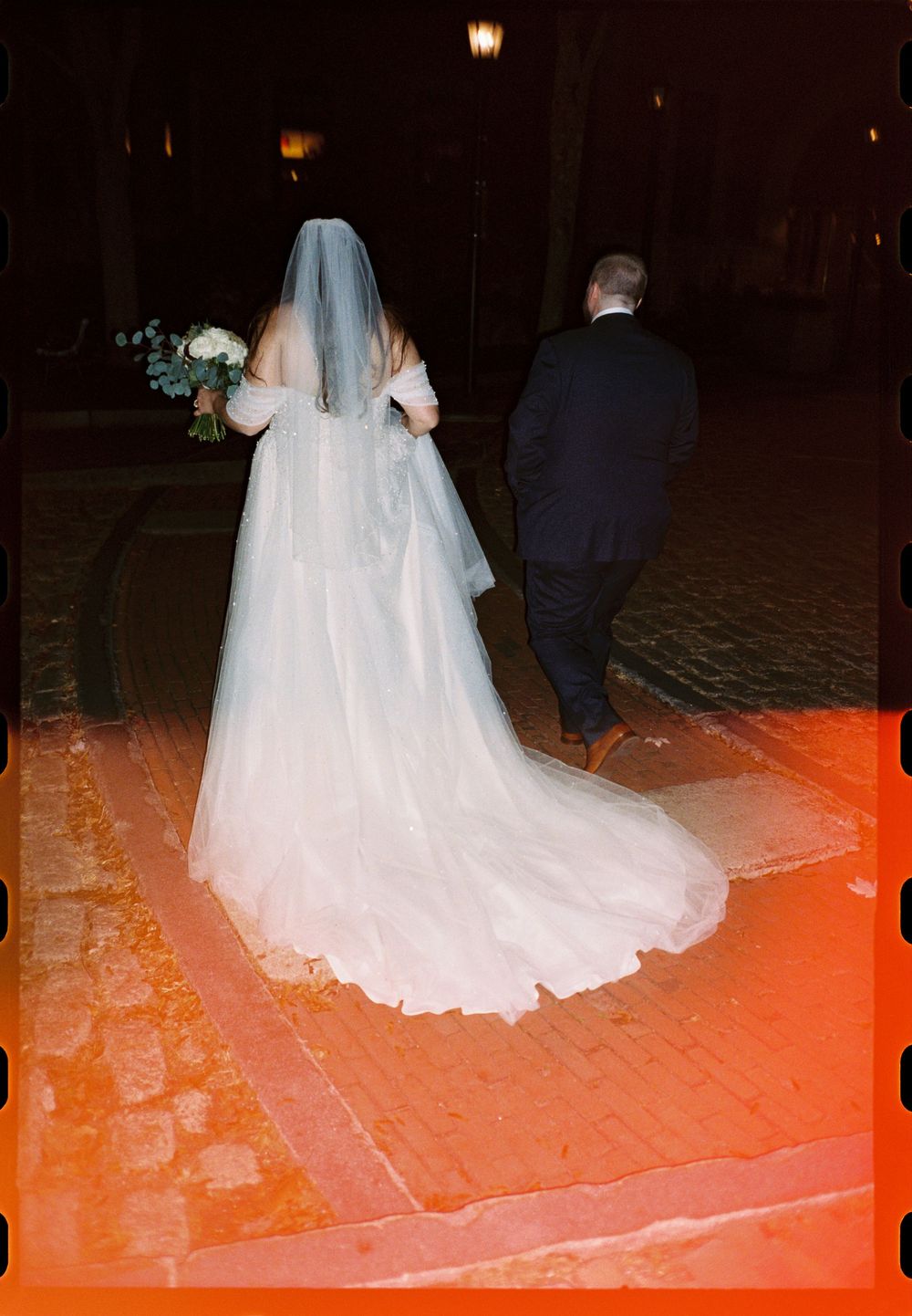 35mm color film photo of the bride and groom walking in downtown Portland, Maine with a focus on the brides dress and train.