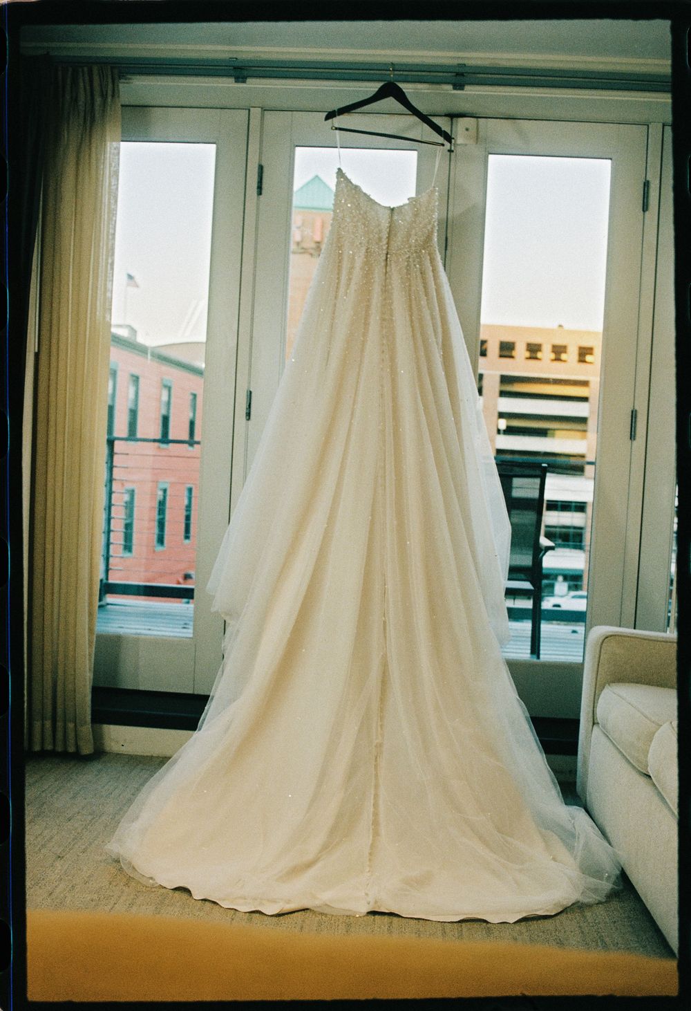 The wedding dress hangs in the window of their hotel room while the bride gets ready for her wedding ceremony at The Regency Hotel.