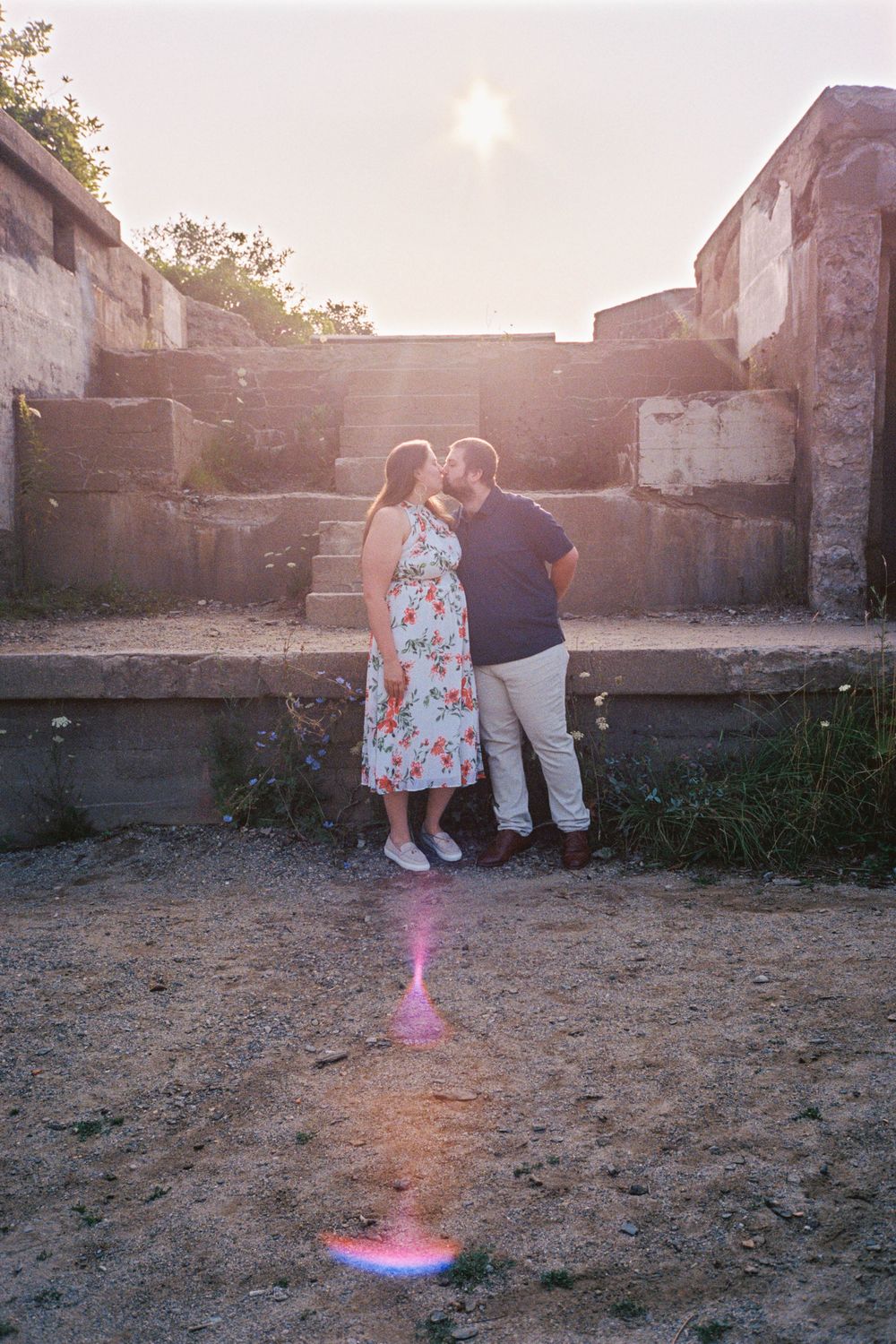 Couple kissing each other under the early morning sunshine near an old fort in the part in Cape Elizabeth, Maine on 35mm film.