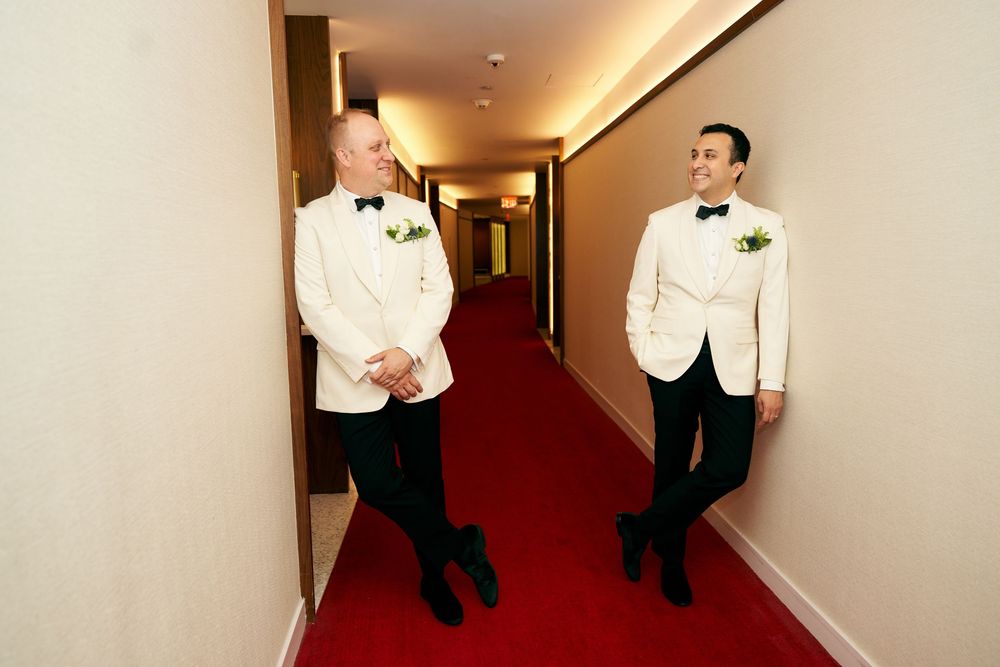 Hallway interior with red carpeting and cream-colored walls showing several formal figures. gay couple wedding  TWA hotel