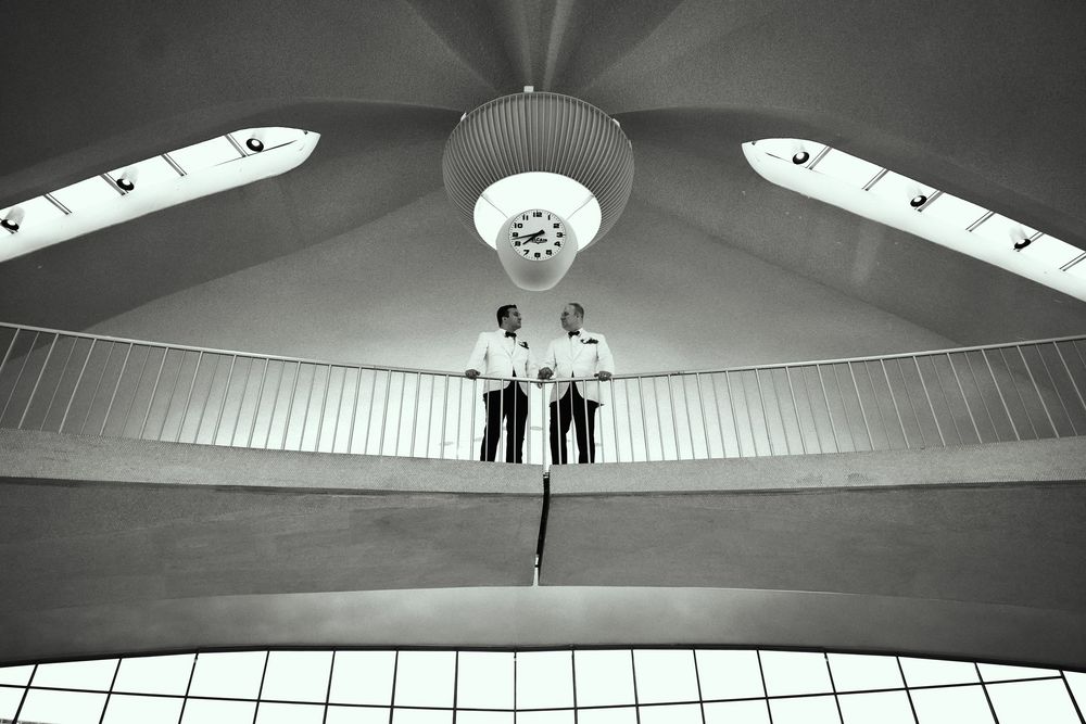 Modern architectural space with vaulted ceiling and geometric lighting fixtures. gay couple wedding  TWA hotel