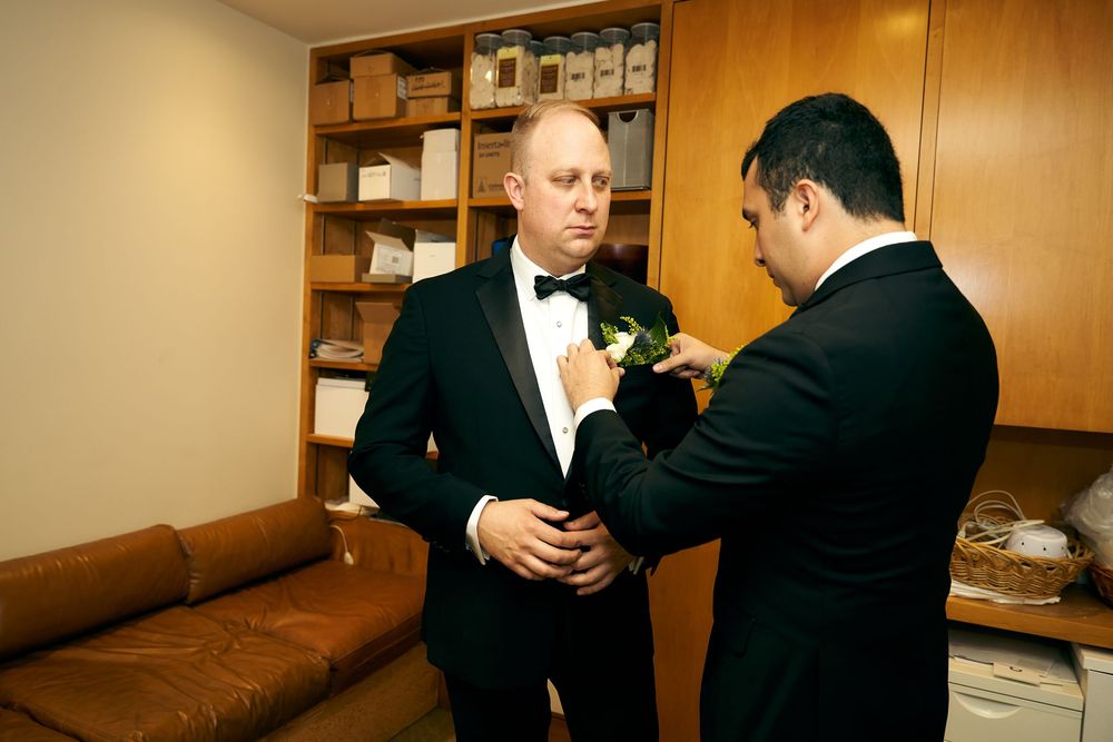 People in formal black and white attire preparing in a room with wood paneling. Siant peters church