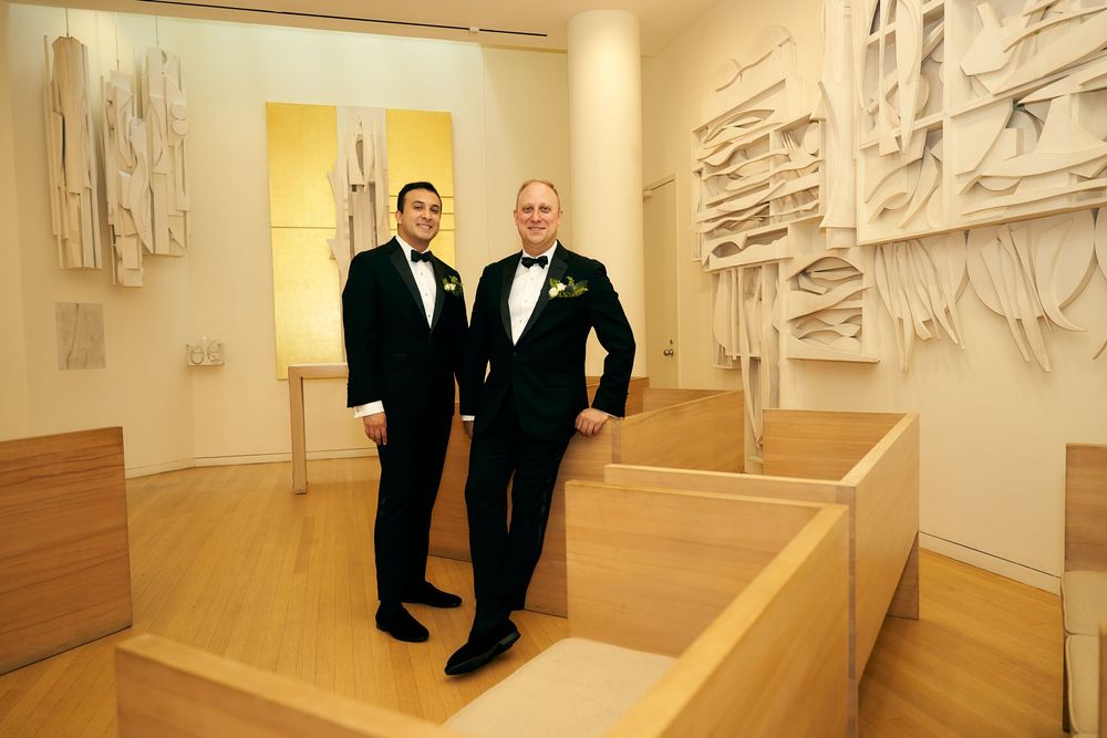 Gallery space with white sculptural wall installations and people in formal attire. Siant peters church
