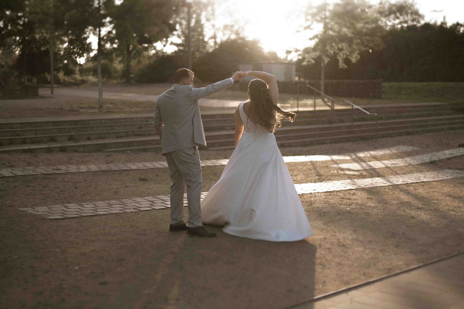 Wedding couple silhouettes against a golden sunset background in an outdoor setting.