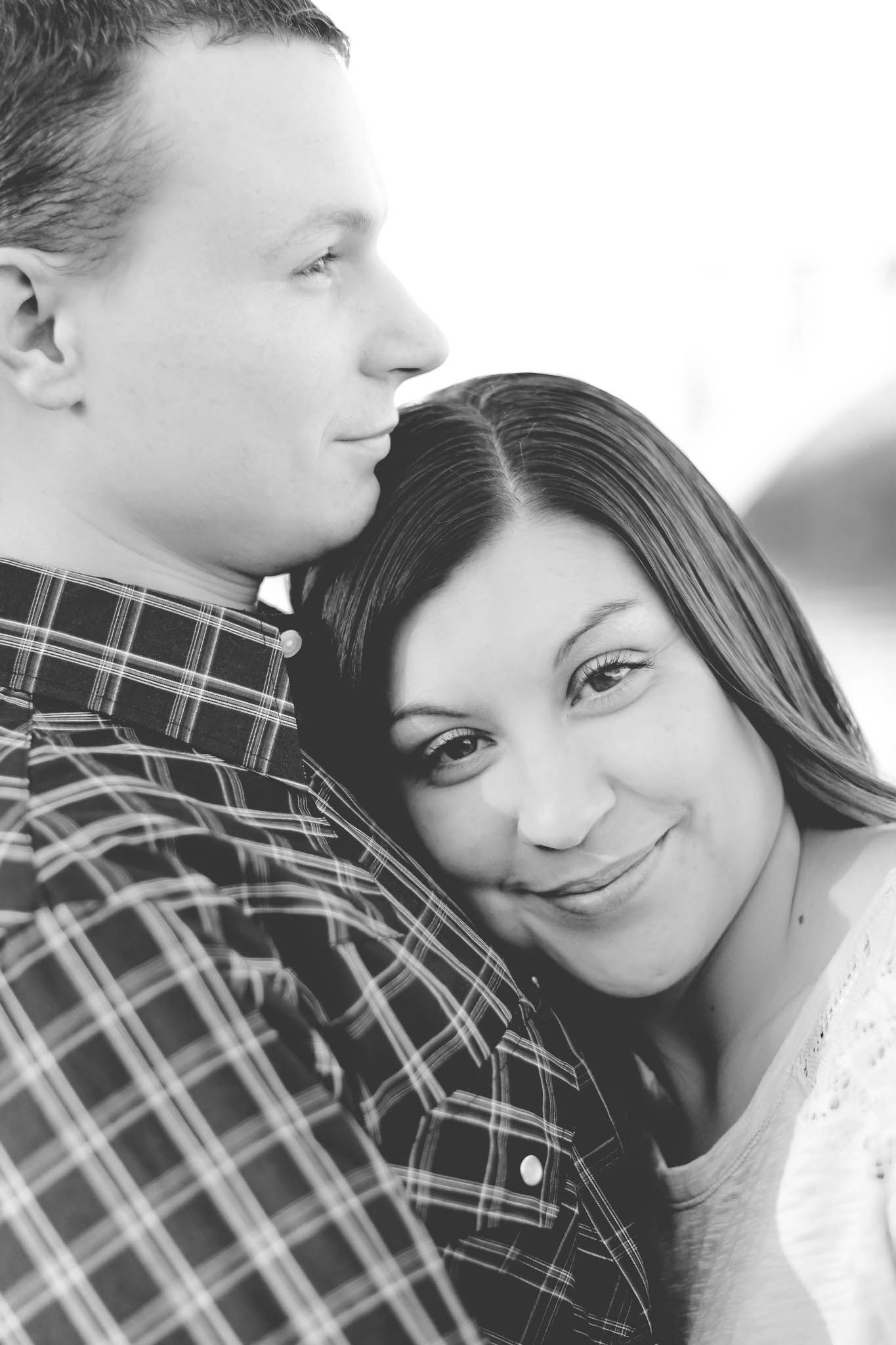 Black and white portrait of a couple in an intimate pose with one wearing a plaid shirt and the other in white.