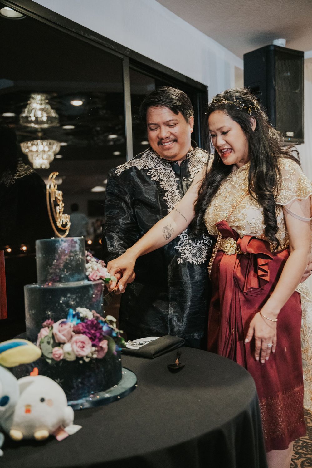 A couple shares a playful moment opening and smashing a festive confetti popper at an indoor celebration.