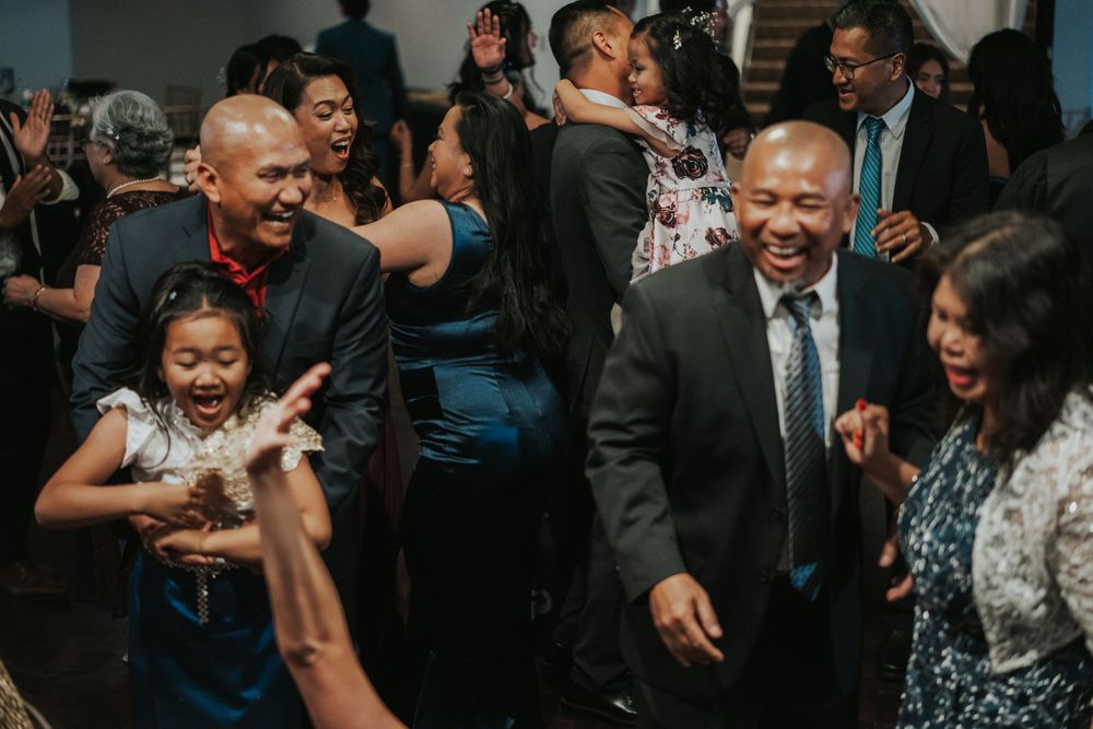People laughing and dancing together at what appears to be a lively party or celebration indoors.