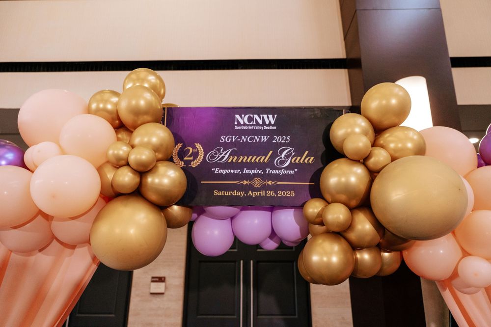 Elegant event decor featuring pink and gold balloon garlands and arches against a dark backdrop.