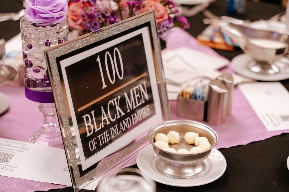 Small black and white chalkboard signs with numbers and text displayed on tables at a formal event.