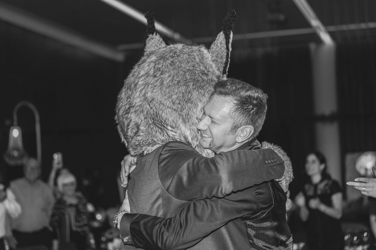 Two wedding guests share an emotional embrace during a reception celebration.