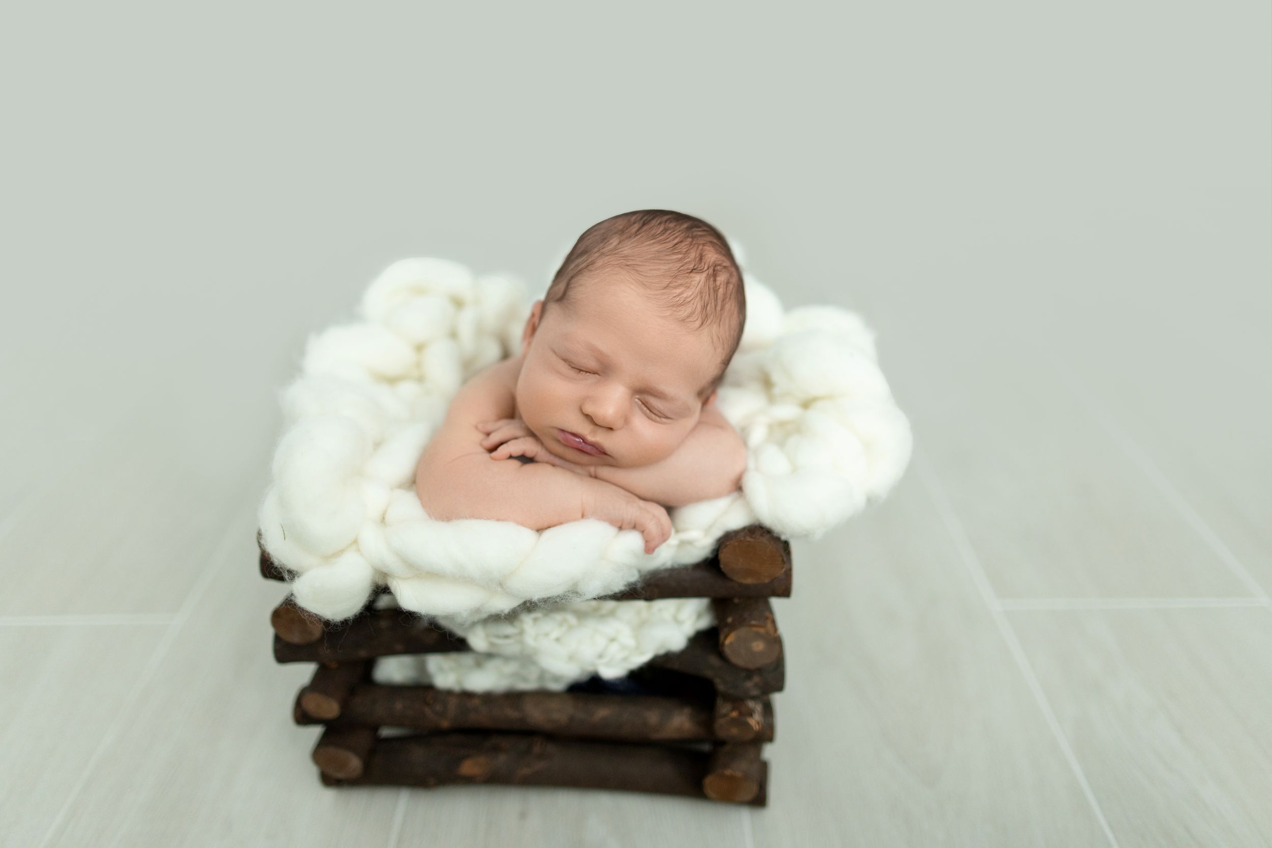 Newborn sleeping on rustic wooden bed with white fluffy bedding. Photos by Tampa Photographer DigitalMyst Photography