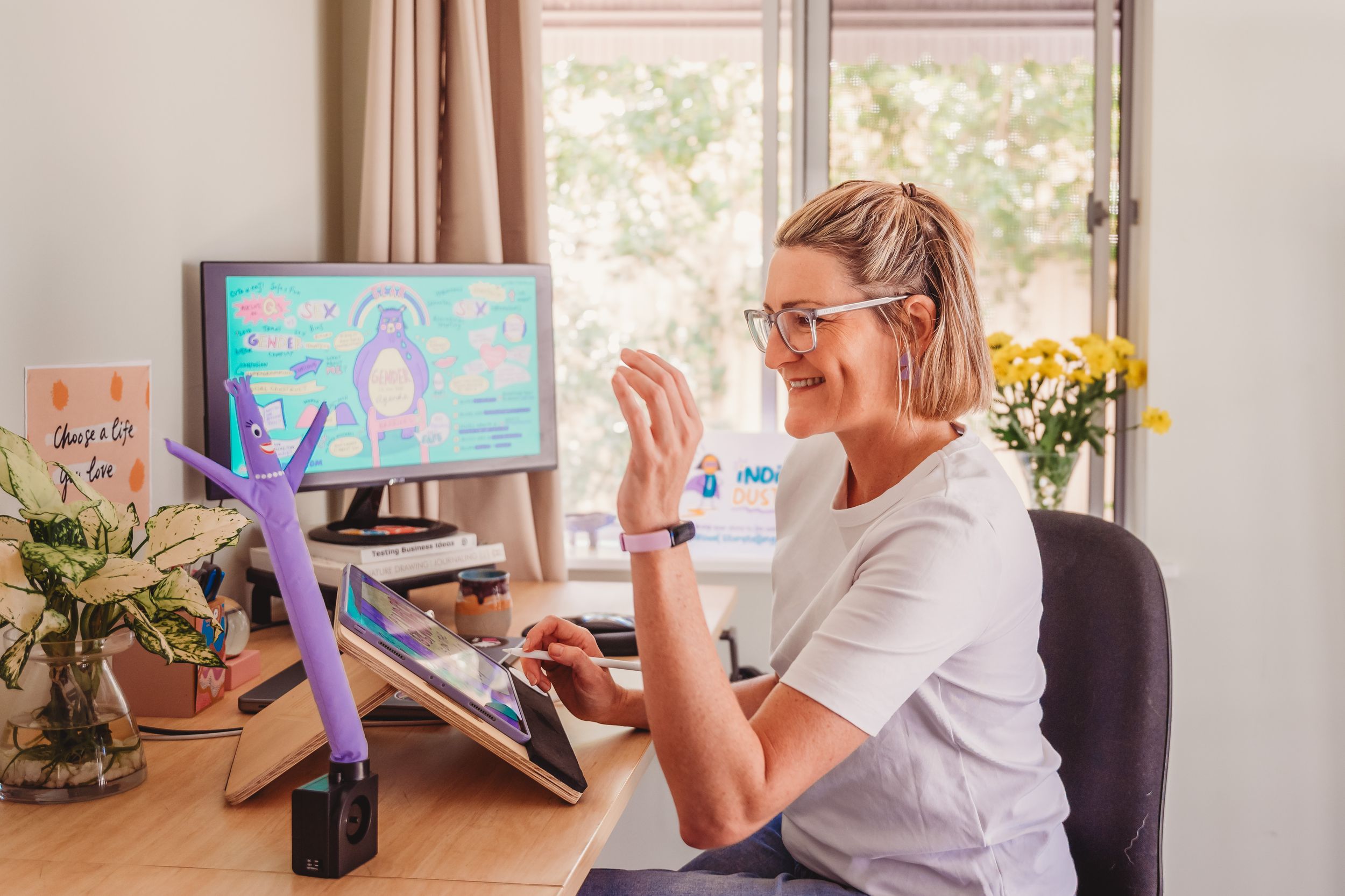 Senior woman making video call on laptop while sitting at home near sunny window with plants.