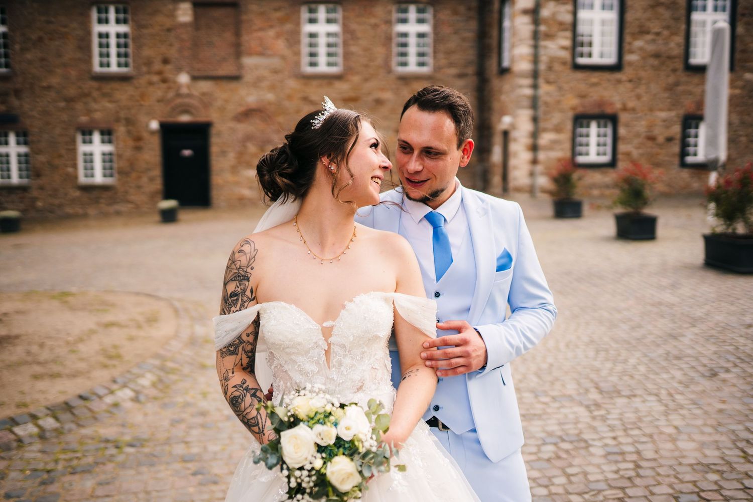 A couple shares an intimate moment in front of a historic brick building on their wedding day.