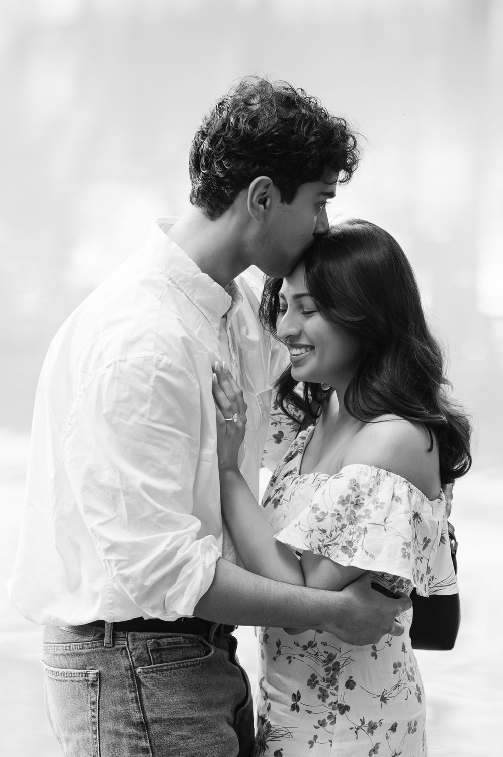 Black and white romantic couple portrait of a man kissing a woman's hair during their surprise proposal in NYC captured by Joliette Marie.