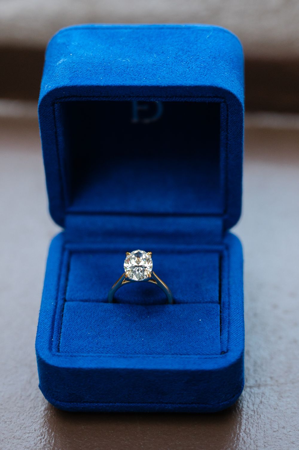 A sparkling diamond engagement ring sits in a royal blue velvet ring box during a surprise NYC proposal