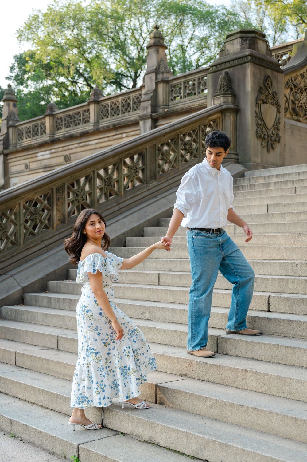 Couple playfully walks up the steps of Bethesda Terrace in Central Park during an early morning engagement session.