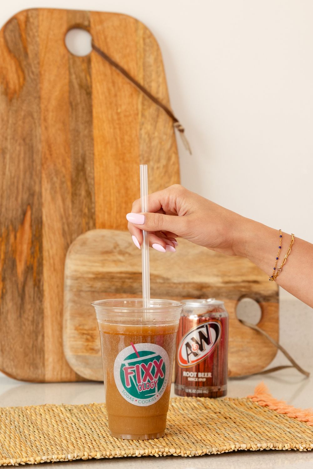 clear cup and woman stirring with straw a&w rootbeer can in the background