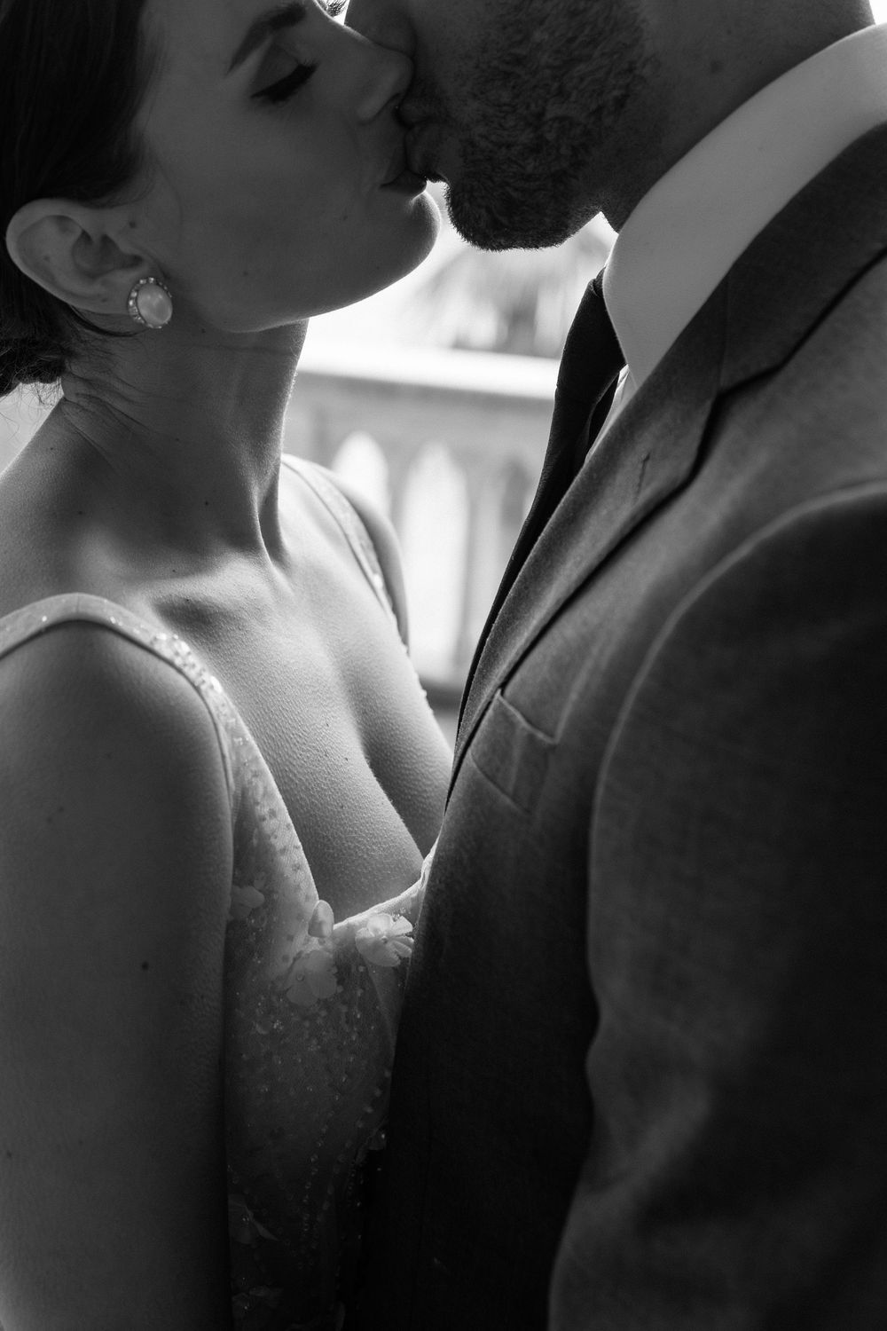 Black and white close-up photos of a romantic couple in formal wedding attire sharing intimate moments together.