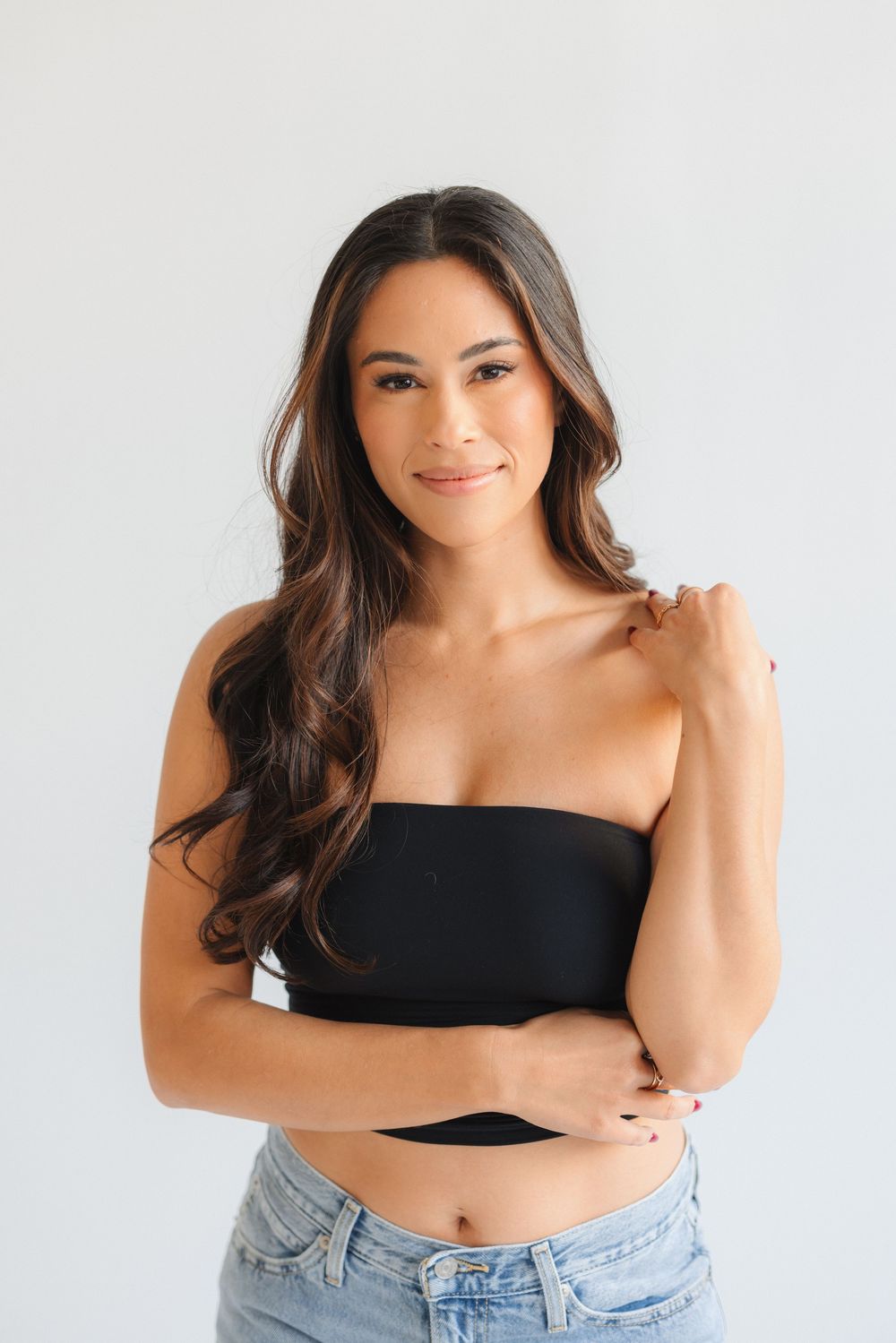 Four portrait photos of woman in black crop top and denim against white background showing different poses.