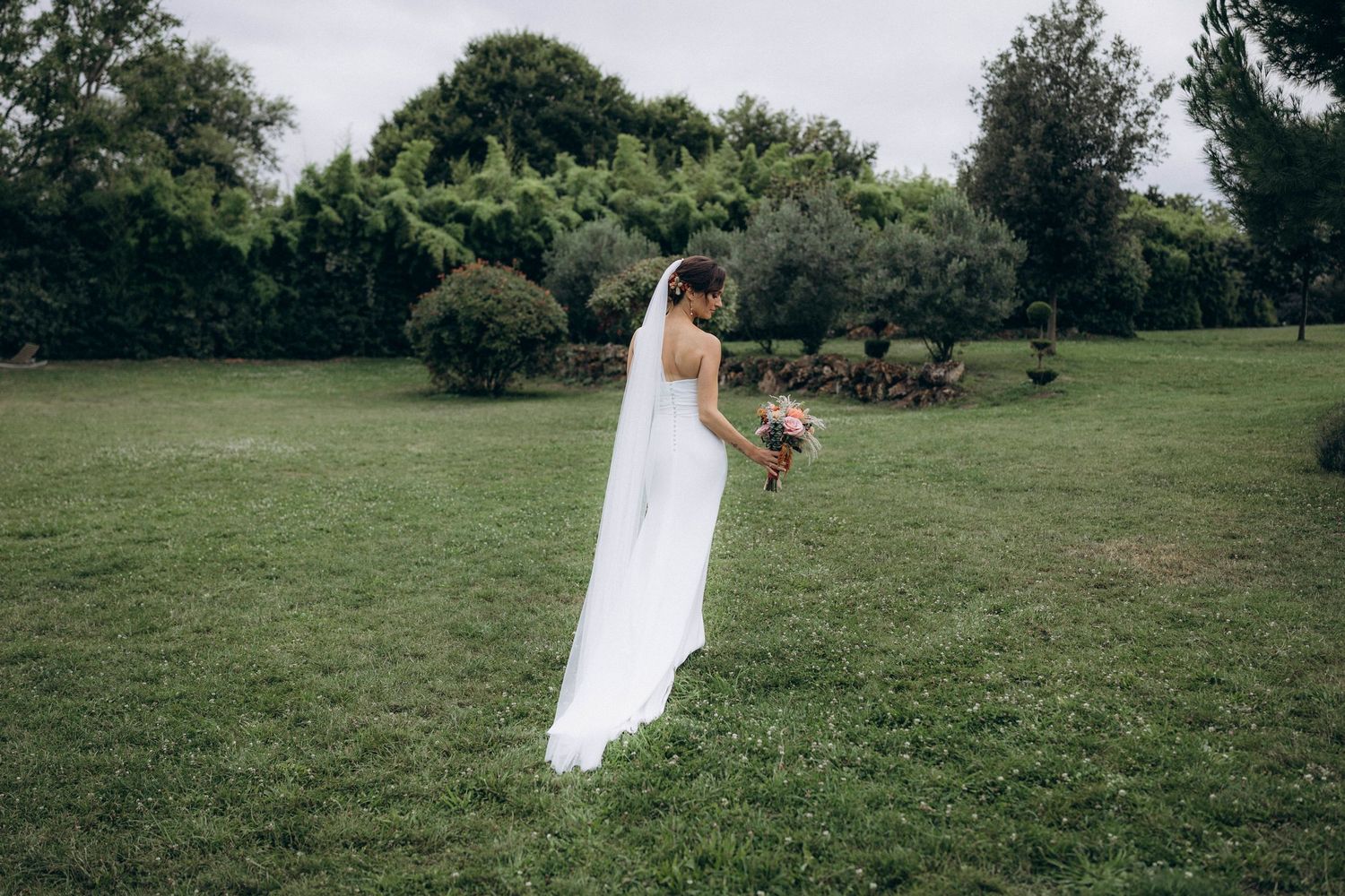 A romantic black and white wedding photograph showing a tender embrace in a natural outdoor setting.