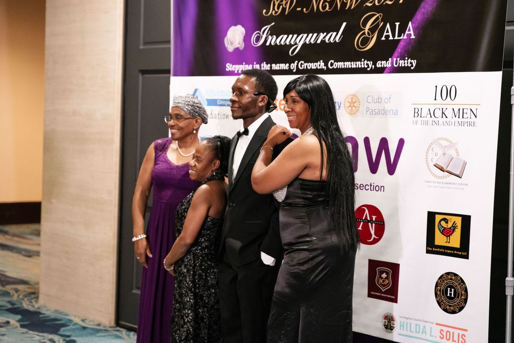 People pose together for a photo at a formal gala event in front of a branded step-and-repeat backdrop.