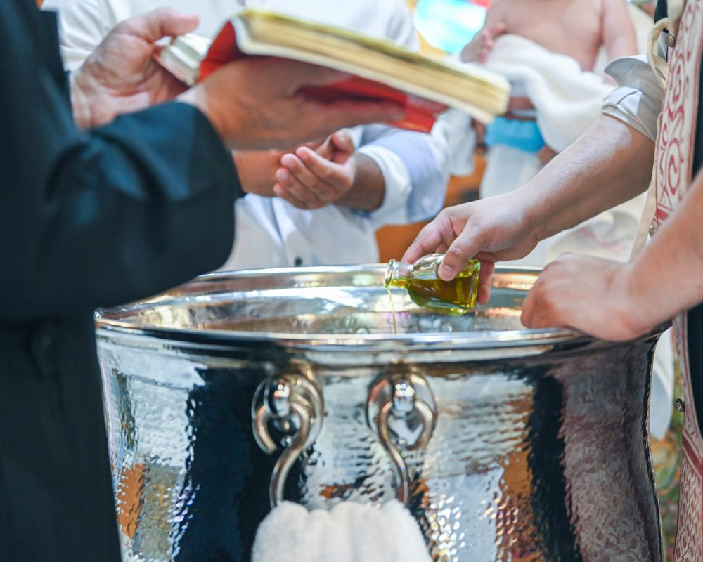 Close up of hands performing baptismal ritual with silver font.